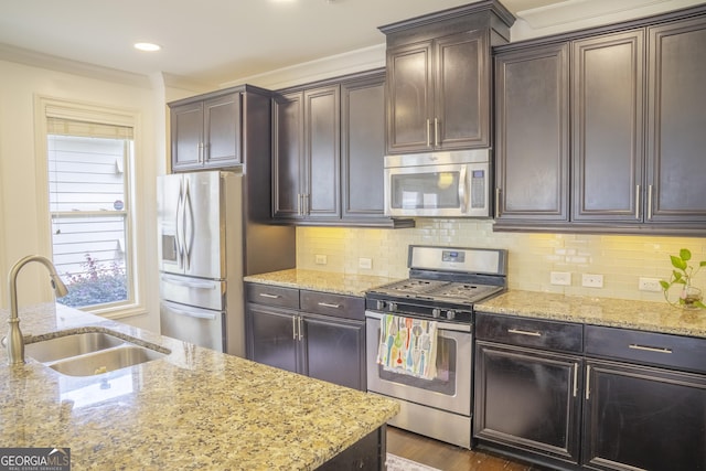 4448 Tacoma Trce, Suwanee, GA 30024 - kitchen with appliances with stainless steel finishes, a sink, light stone countertops, dark brown cabinets, and crown molding