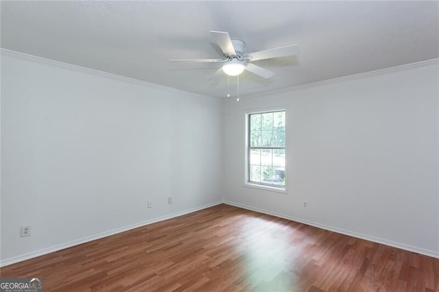 spare room with wood finished floors, a ceiling fan, baseboards, and crown molding