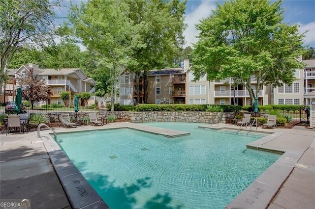 community pool with a residential view, fence, and a patio
