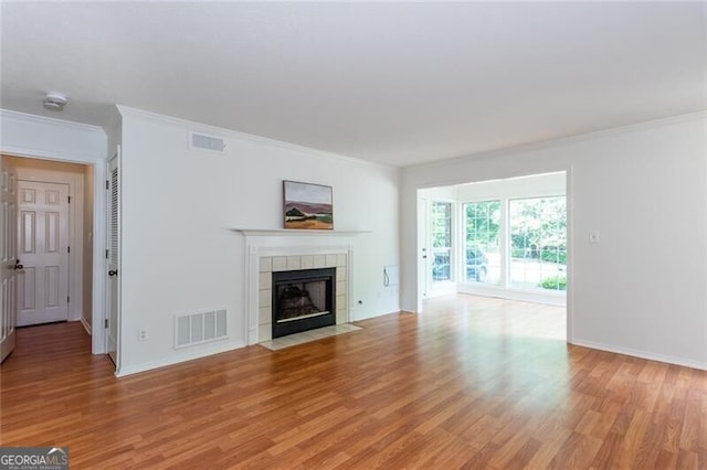 unfurnished living room with light wood finished floors, a fireplace, ornamental molding, and baseboards
