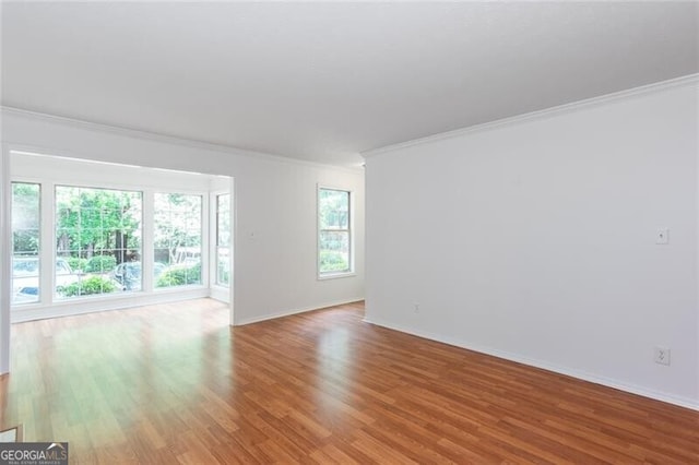 spare room featuring ornamental molding, wood finished floors, and baseboards