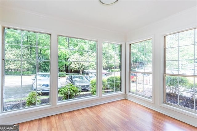 unfurnished sunroom with ornamental molding and wood finished floors
