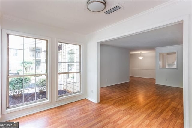 unfurnished room featuring crown molding, light wood-style flooring, and baseboards