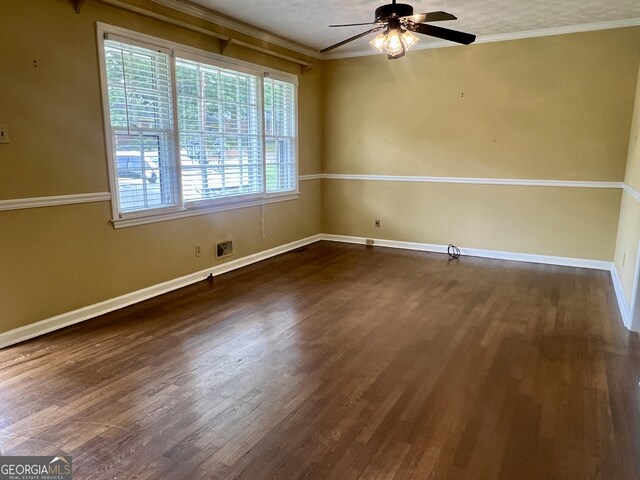 empty room with healthy amount of natural light, dark wood-style flooring, ceiling fan, ornamental molding, and baseboards