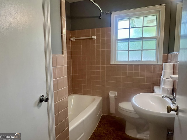 bathroom with tile walls, toilet, a wainscoted wall, and shower / washtub combination