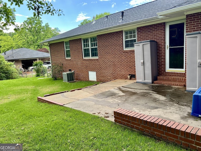 back of property featuring entry steps, brick siding, a patio, a yard, and roof with shingles