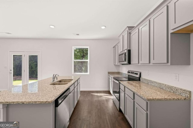 kitchen featuring stainless steel appliances, a sink, gray cabinetry, a kitchen island with sink, and baseboards
