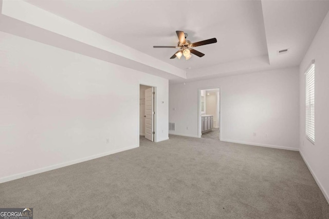 unfurnished bedroom with a tray ceiling, baseboards, and carpet