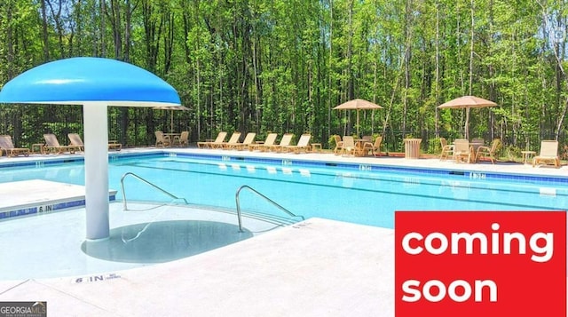 community pool featuring fence and a view of trees