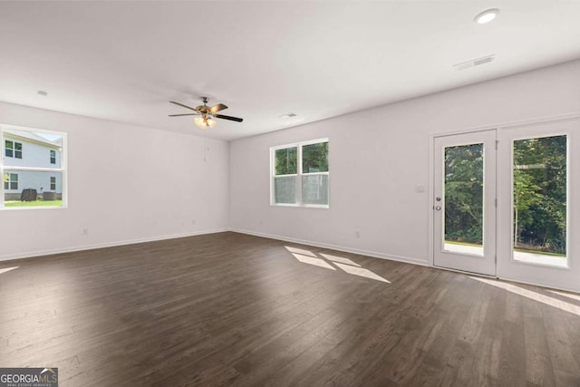 empty room featuring plenty of natural light, dark wood-style floors, and baseboards