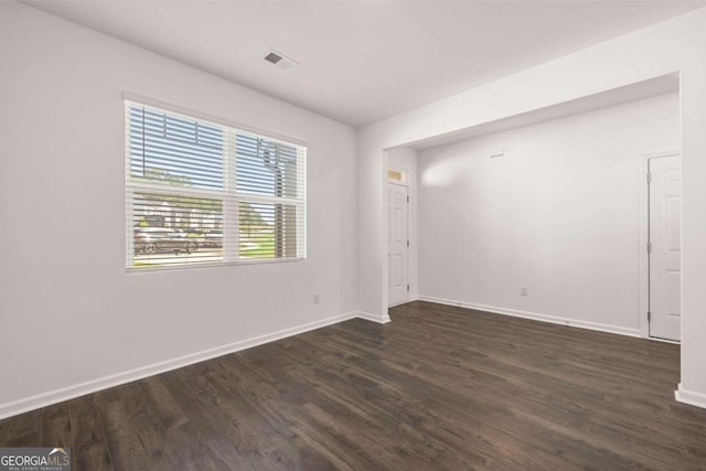empty room with dark wood-style flooring and baseboards