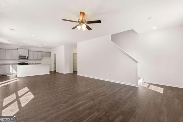 unfurnished living room featuring a ceiling fan, recessed lighting, baseboards, and dark wood-style floors