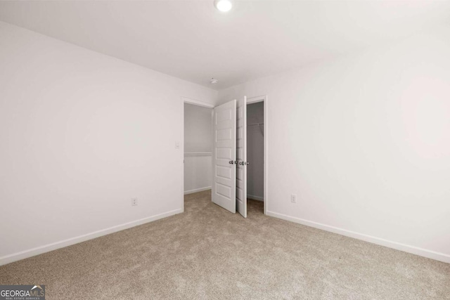 unfurnished bedroom with carpet floors, baseboards, a walk in closet, a closet, and recessed lighting