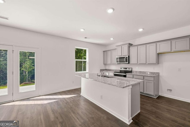 kitchen with stainless steel appliances, gray cabinets, dark wood-style flooring, a sink, and baseboards