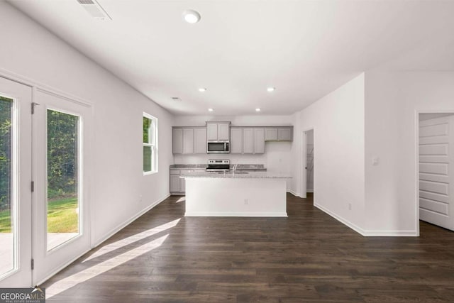 kitchen featuring appliances with stainless steel finishes, gray cabinets, recessed lighting, a kitchen island with sink, and dark wood-type flooring