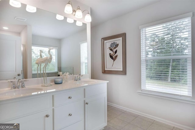 bathroom featuring plenty of natural light, baseboards, tile patterned floors, and double vanity