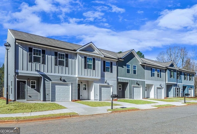 view of property with board and batten siding, an attached garage, concrete driveway, and a residential view