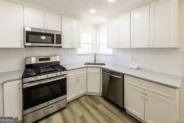 2192 Stenger Rd, Douglasville, GA 30135 - kitchen with appliances with stainless steel finishes, a sink, light countertops, light wood-type flooring, and white cabinetry