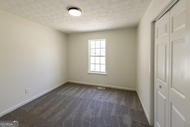 2192 Stenger Rd, Douglasville, GA 30135 - unfurnished bedroom featuring dark carpet, a textured ceiling, and baseboards