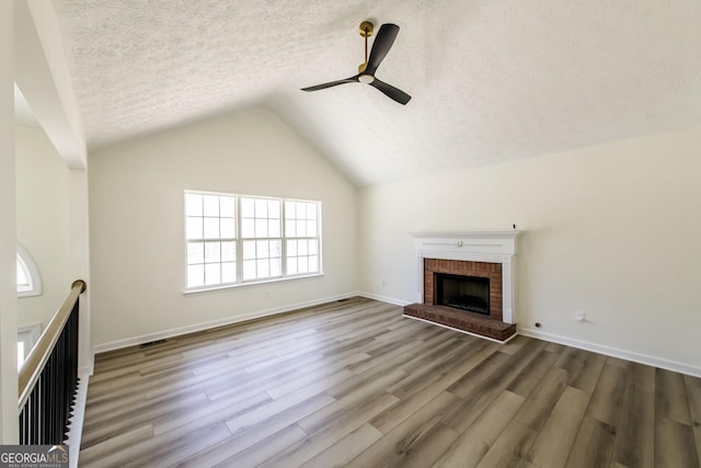 2192 Stenger Rd, Douglasville, GA 30135 - unfurnished living room featuring wood finished floors, ceiling fan, a textured ceiling, lofted ceiling, and a fireplace