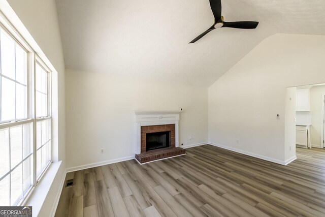 2192 Stenger Rd, Douglasville, GA 30135 - unfurnished living room featuring vaulted ceiling, ceiling fan, plenty of natural light, wood finished floors, and a brick fireplace