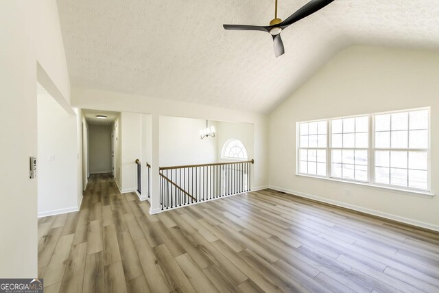 2192 Stenger Rd, Douglasville, GA 30135 - unfurnished room featuring a textured ceiling, ceiling fan, wood finished floors, vaulted ceiling, and a chandelier