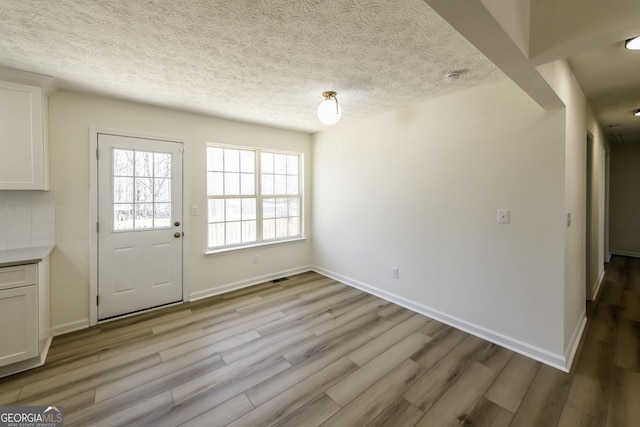 2192 Stenger Rd, Douglasville, GA 30135 - unfurnished dining area with light wood-style flooring, baseboards, and a textured ceiling