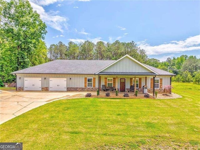 view of front of house featuring a porch, a front lawn, driveway, a garage, and board and batten siding