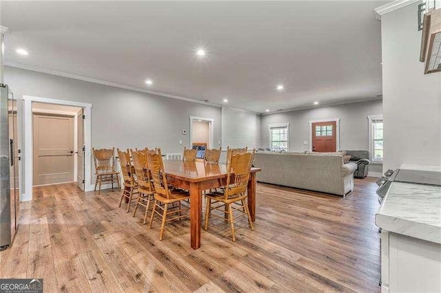 dining space featuring light wood finished floors, ornamental molding, recessed lighting, and baseboards