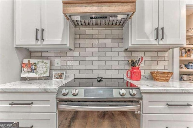 kitchen with electric range, custom range hood, white cabinetry, tasteful backsplash, and light stone counters
