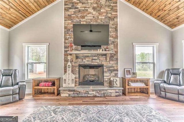 living room with lofted ceiling, wood ceiling, a stone fireplace, wood finished floors, and plenty of natural light