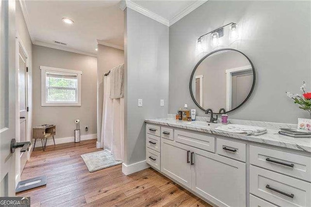 bathroom with crown molding, wood finished floors, vanity, baseboards, and recessed lighting