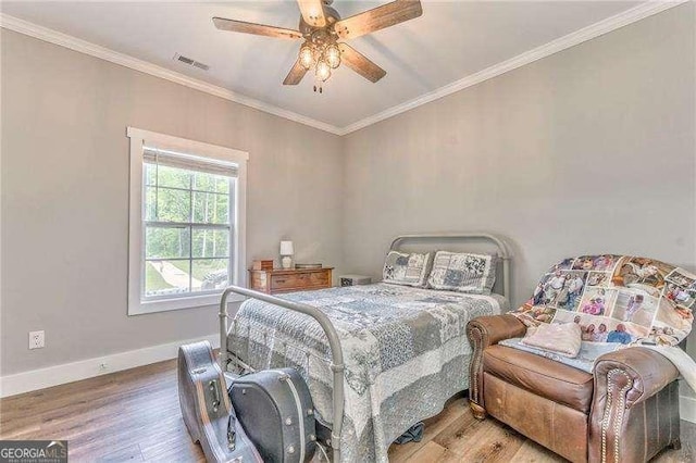 bedroom featuring wood finished floors, crown molding, baseboards, and a ceiling fan