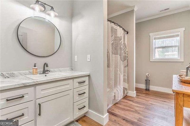 bathroom featuring crown molding, baseboards, wood finished floors, and vanity