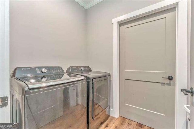 laundry area with washer and clothes dryer, ornamental molding, and light wood-type flooring