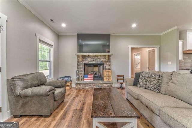 living room featuring wood finished floors, crown molding, a fireplace, recessed lighting, and baseboards