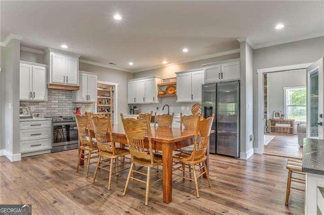 dining area with ornamental molding, wood finished floors, recessed lighting, and baseboards