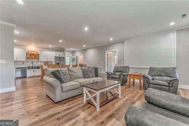 living room featuring crown molding, light wood-style flooring, recessed lighting, and baseboards