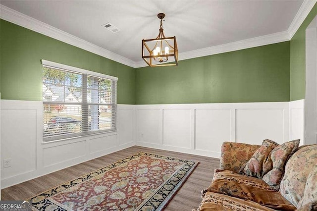 1511 Arica Ave, Lawrenceville, GA 30043 - sitting room featuring a chandelier, crown molding, a wainscoted wall, a decorative wall, and wood finished floors
