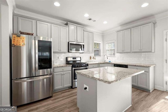 1511 Arica Ave, Lawrenceville, GA 30043 - kitchen featuring stainless steel appliances, wood finished floors, crown molding, tasteful backsplash, and gray cabinets