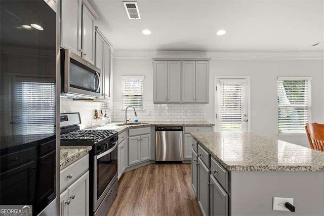 1511 Arica Ave, Lawrenceville, GA 30043 - kitchen with stainless steel appliances, a sink, gray cabinetry, crown molding, and wood finished floors