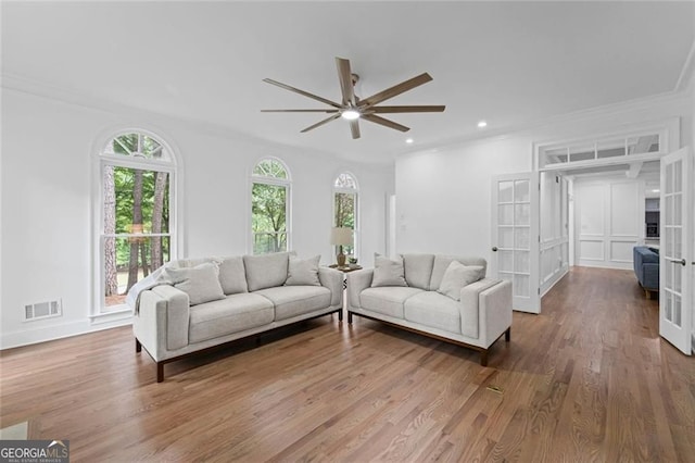 living room with ornamental molding, plenty of natural light, a ceiling fan, wood finished floors, and recessed lighting