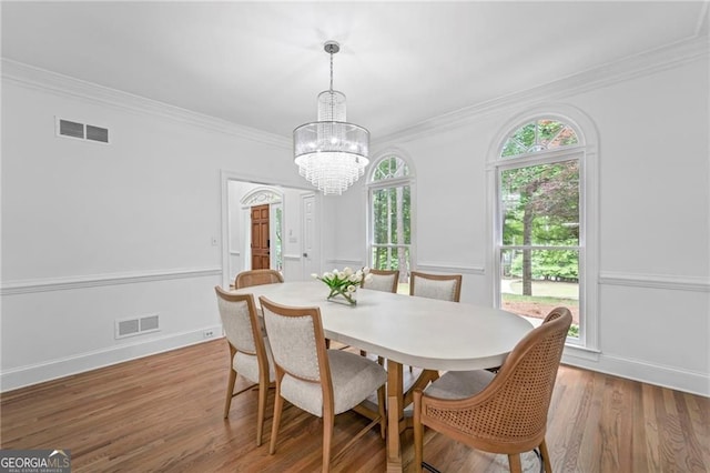 dining room featuring a chandelier, wood finished floors, crown molding, and baseboards