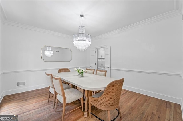 dining room with a chandelier, crown molding, wood finished floors, and baseboards