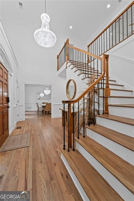 entrance foyer featuring a chandelier, stairway, wood finished floors, recessed lighting, and a high ceiling