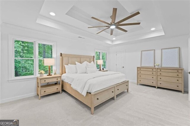 bedroom with a raised ceiling, recessed lighting, light carpet, baseboards, and ceiling fan