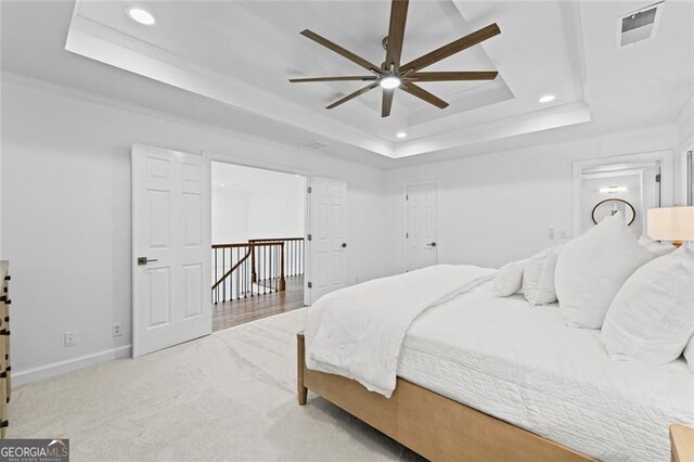 bedroom with a tray ceiling, recessed lighting, baseboards, carpet floors, and ornamental molding
