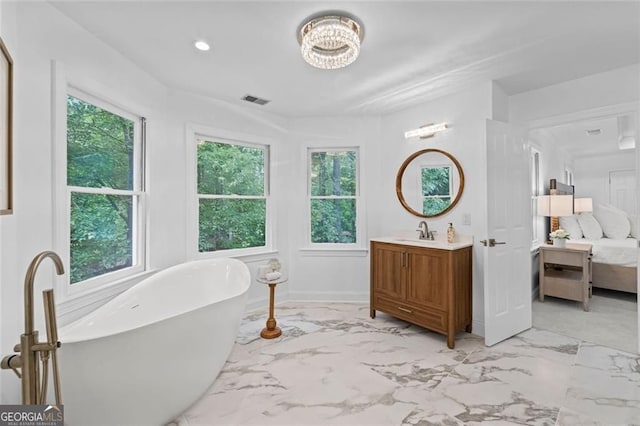 full bathroom featuring marble tiled flooring, ensuite bathroom, a freestanding bath, vanity, and baseboards