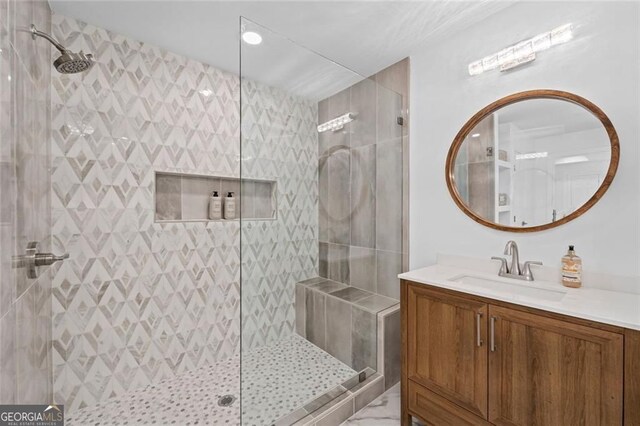 bathroom featuring tiled shower and vanity