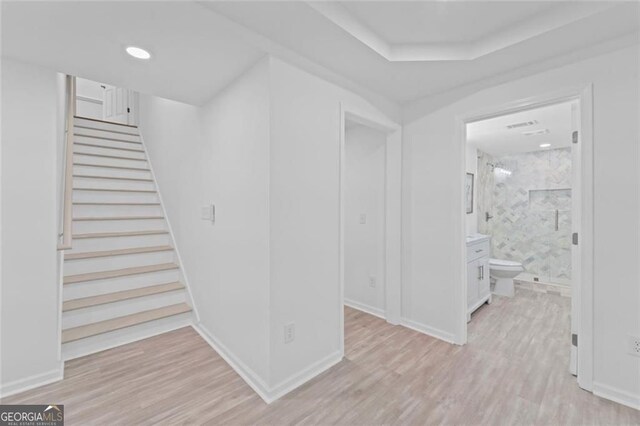 hallway featuring light wood-type flooring, stairs, recessed lighting, and baseboards